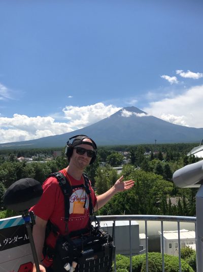 Joe Bohannon in red shirt with full audio rig pointing at Mount Fuji Japan