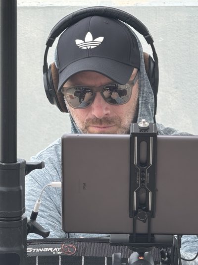 Joe Bohannon monitoring audio on tablet with headphones on set