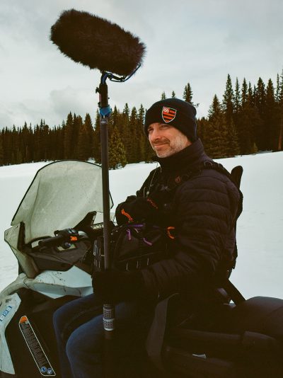 Joe Bohannon on snowmobile in winter mountain location with boom mic
